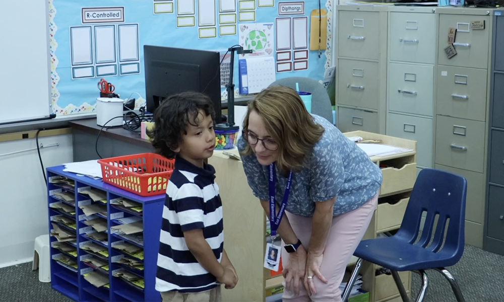 Teacher leaning down and speaking with a kindergarten student