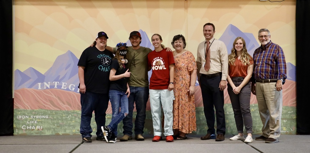 Family members and the mural artist pose in front of the mural.