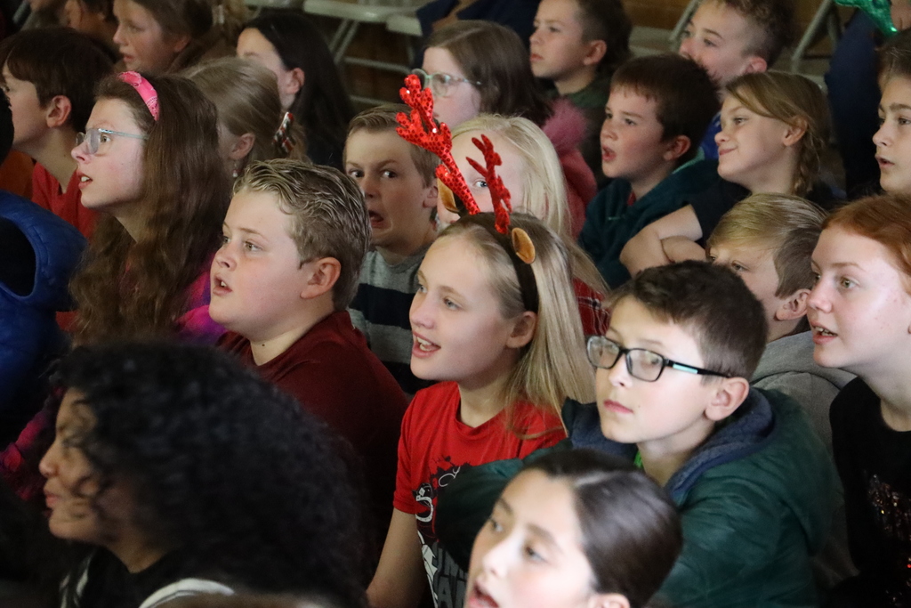 A students sings with reindeer antlers on her head.